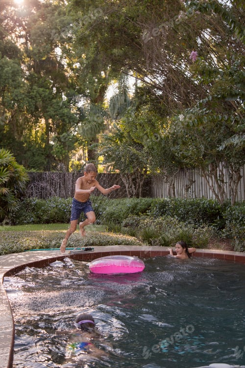 Preview: Children swimming in garden pool, young boy jumping in, mid-air