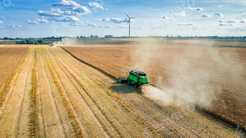 Preview: Harvester on field and wind turbine on background, aerial view