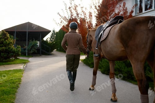 Preview: Back view of woman equestrian holding saddle strap