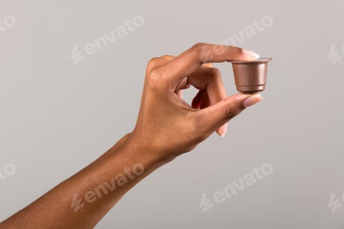 Preview: Black female hand showing coffee capsule