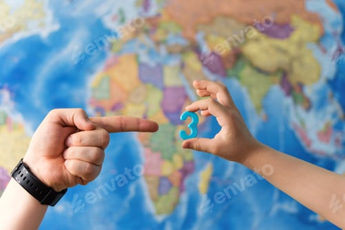 Preview: Adult And Child Hands Holding Numbers Plastic Toy On The World Political Map Background. Travel