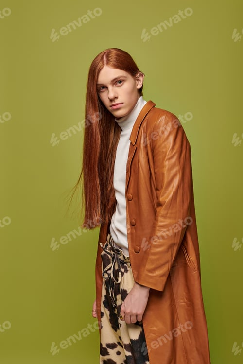 Preview: Young man with long red hair expresses deep emotions against a vibrant green background