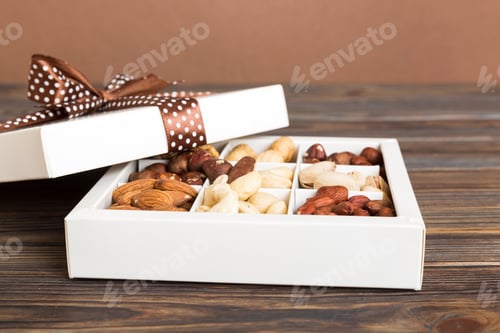 Preview: Various varieties of nuts lying in paper box on table background.