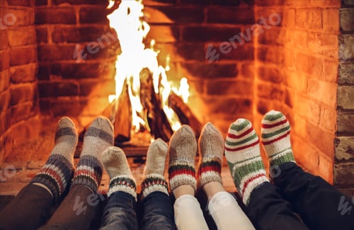 Preview: Family mother, father and kids wearing warm woolen socks warming feet by fireplace on Christmas time