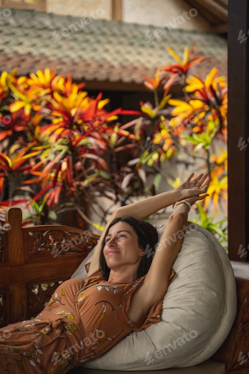 Preview: Woman Relaxing Outdoors on Daybed Surrounded by Plants