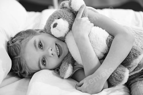 Preview: Smiling little girl with teddy bear lying in hospital bed, black and white photo
