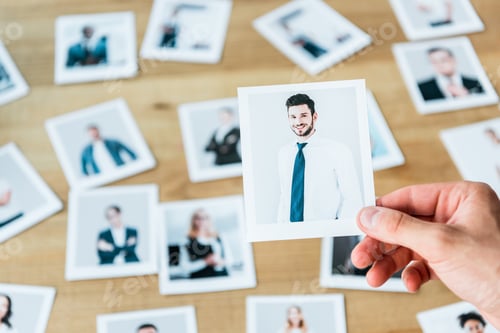 Preview: cropped view of recruiter holding photo with man in suit
