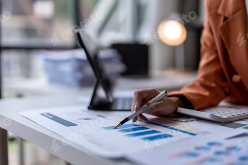 Preview: Businesswoman analyzing financial charts and data on office desk