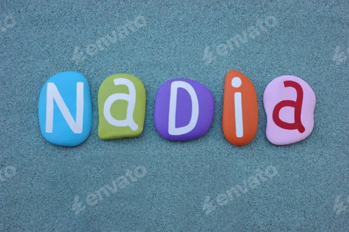 Preview: Nadia, female given name composed with multi colored stone letters over green sand