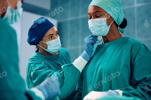 Preview: Black female doctor sweating during an exhausting surgery in operating room.