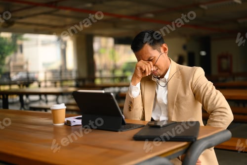 Preview: Tired businessman taking glasses off, rubbing eyelids after long computer work