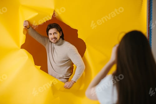 Preview: Backstage advertising photo shoot. Young handsome man posing on torn paper background.