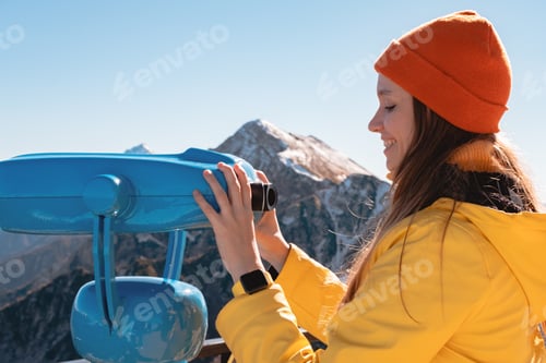Preview: Young woman looking through binocular for viewing platforms on a beautiful autumn mountain landscape