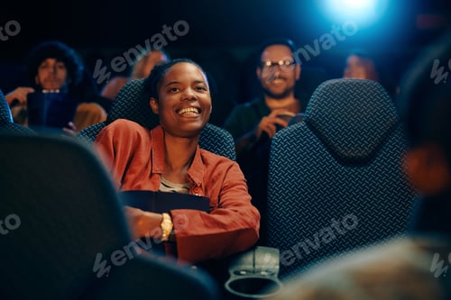 Preview: Happy black woman enjoying in watching a movie at cinema.