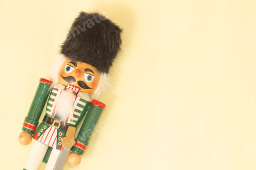 Preview: Interesting beautiful christmas nutcracker soldier on yellow colored paper surface texture with copy