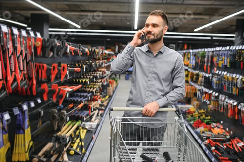 Preview: male builder in a hardware store chooses a tools