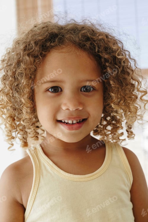 Preview: Smiling child with curly hair enjoying a sunny day indoors