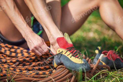 Preview: Close up of rock climber putting on climbing shoes while sitting on grass