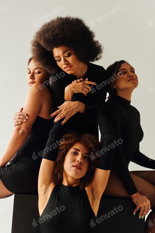 Preview: attractive african american women in black alluring outfits posing on black cube, fashion concept