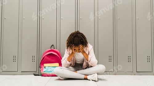 Preview: Troubles at school. Lonely sad african-american schoolgirl crying at school hall