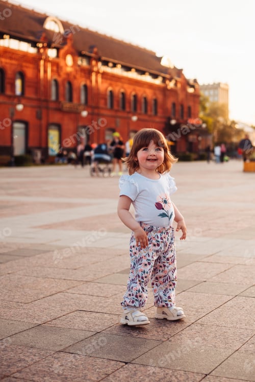 Preview: little girl playing having fun outdoors in the city in summer at sunset