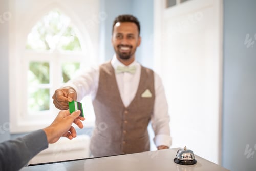 Preview: A man is paying with a credit card at a hotel reception desk