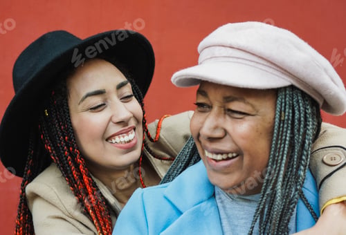 Preview: Happy african daughter hugging her mother in the city during winter time