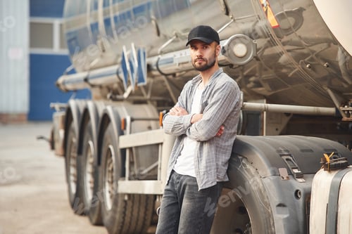 Preview: Leaning on the vehicle. Young truck driver in casual clothes