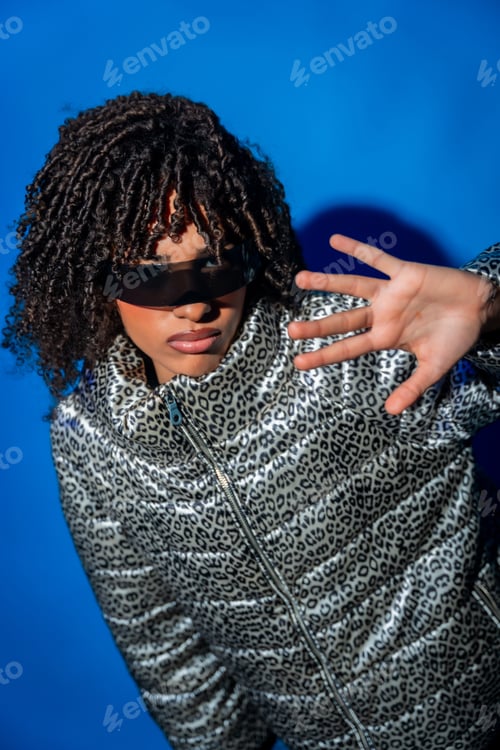 Preview: Fashion model wearing sunglasses and animal print jacket posing on blue background