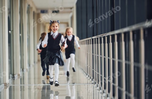Preview: Active school kids in uniform running together in corridor. Conception of education