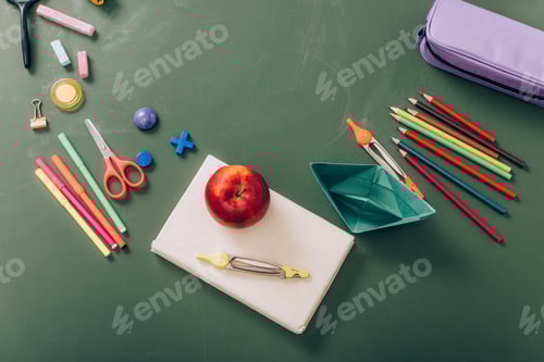Visualização: vista superior de maçã madura e divisória de bússola em livro perto de um barco de papel e material escolar em verde