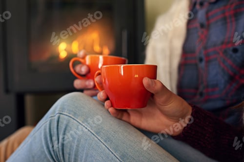Preview: Cropped shot of a young couple drinking hot chocolate by the fireplace