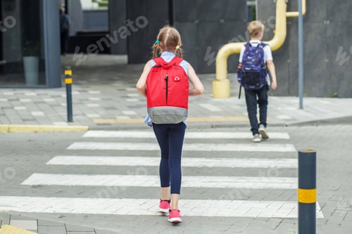 Preview: Back to school. Little pedestrians with backpacks walk to school and cross road at crosswalk