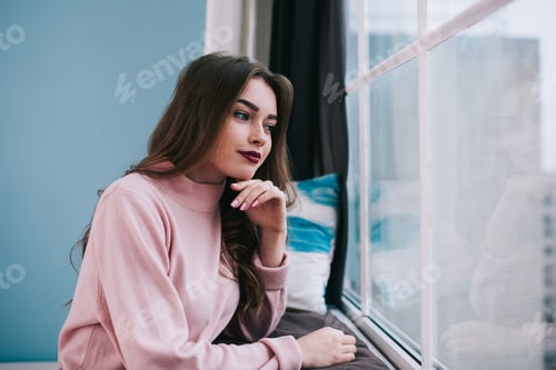 Preview: Thoughtful Woman Relaxing by the Window Indoors