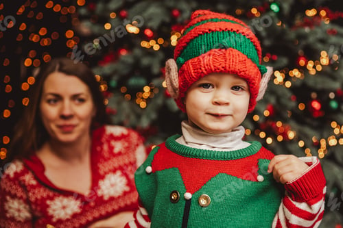 Preview: Happy family under Christmas tree. baby boy in Santa Claus hat with gifts under Christmas tree with