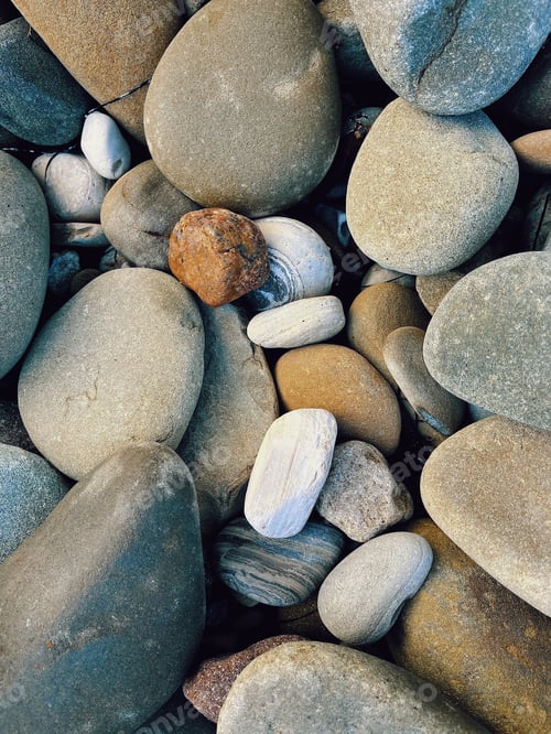 Preview: Different shapes and colored rocks are nestled together on a rocky beach in California