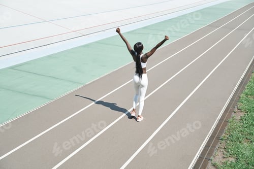 Preview: Top view of beautiful young African woman in sports clothing keeping arms raised