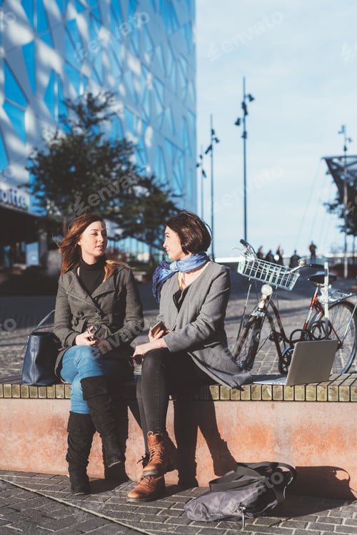 Preview: two young women sitting outdoor chatting
