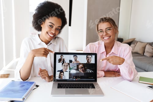 Preview: Multicultural girls pointing fingers at laptop while making conference call