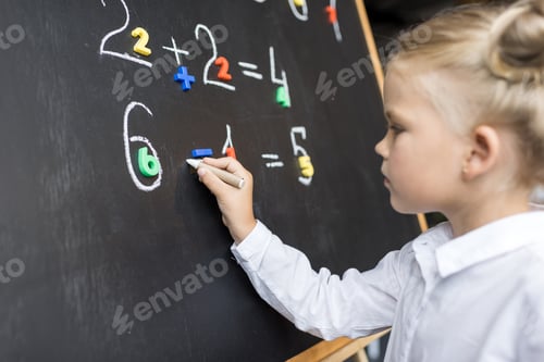 Preview: focused elementary school student studying mathematics on blackboard