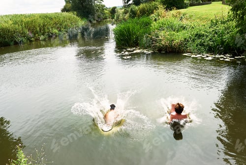 Preview: Young man and teenage boy splashing into rural lake