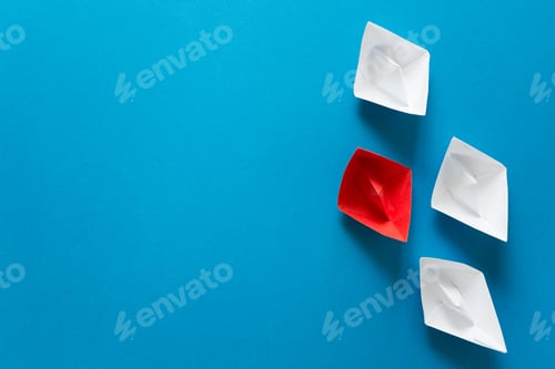 Preview: Set of red and white origami boats on blue paper background