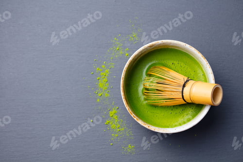 Preview: Matcha Green Tea Cooking Process in a Bowl with Bamboo Whisk. Black Slate Background.