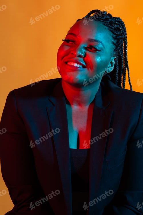 Preview: Close up beauty fashion portrait of an attractive young african woman wearing dreadlocks over orange