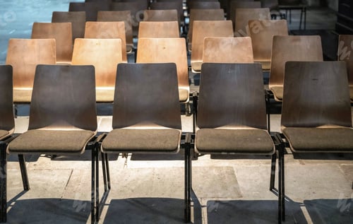Preview: Row of empty wooden chairs in an auditorium