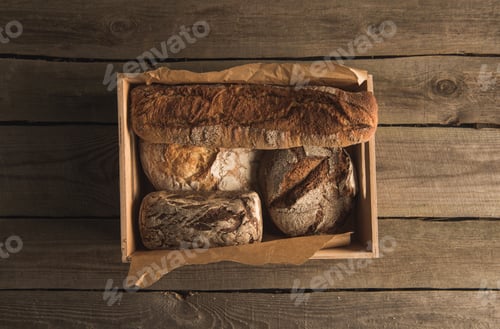 Preview: top view of assorted fresh homemade bread in box on table