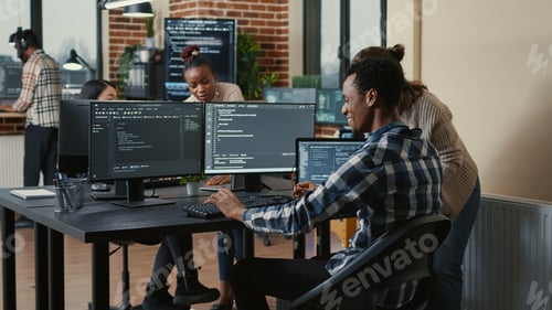 Preview: Software developer looking at running code on multiple screens takes off glasses and doing high five
