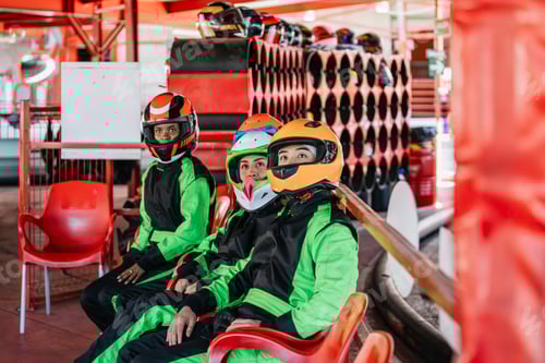 Preview: Friends wearing helmets and racing suits at go kart track