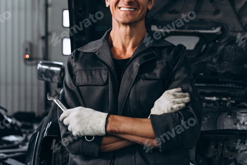 Preview: Cropped view of the auto mechanic standing near opened car outdoors and holding wrench