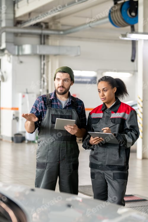 Preview: Young repairman in uniform describing female colleague characteristics of car
